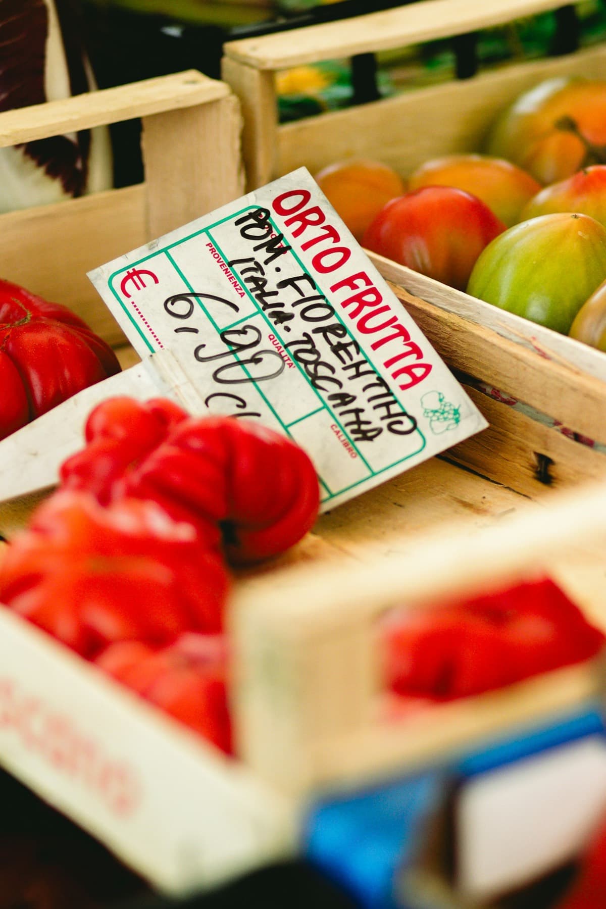 Caisses de tomates à l'étal d'un marché, étiquette à la main.